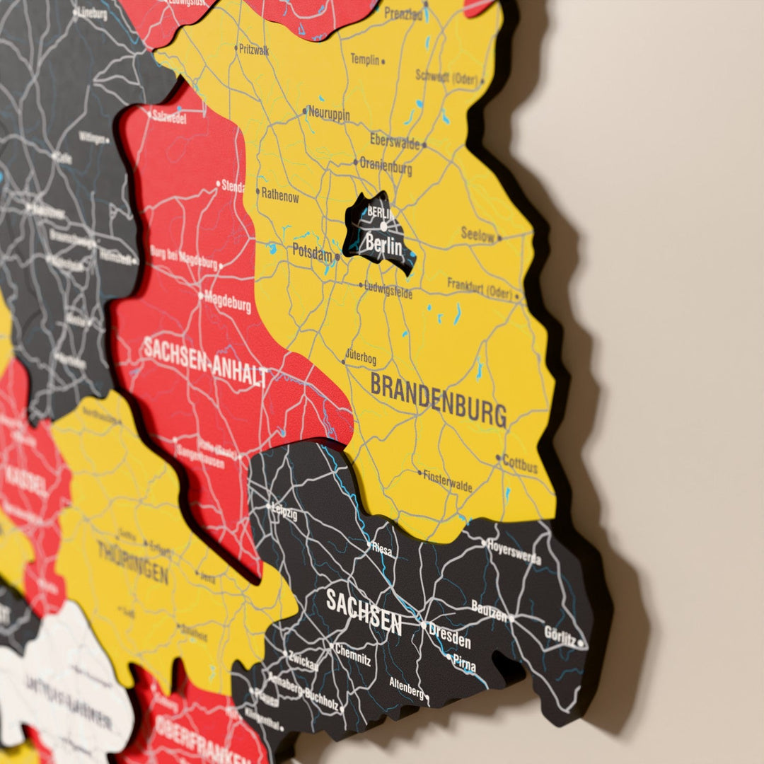 Almanya ahşap haritasında bayrak renkli katmanlı bölgeler ve isimler, yakın plan