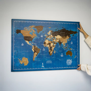 Ocean dünya haritası kanvas tablo, 112x80 cm, duvara asılırken iki elle tutulan görünüm