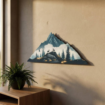 Dağ silüeti ve geyik figürlü metal tablo, 67x27 cm, bej duvarda yandan görünüm, eğrelti otu yanında