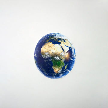 Afrika kıtası görünümlü yuvarlak metal dünya tablosu, beyaz duvarda uzak plan