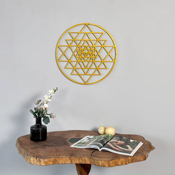 Altın Sri Yantra kutsal geometri metal duvar tablosu, ahşap konsol ve çiçek vazosunun üstünde