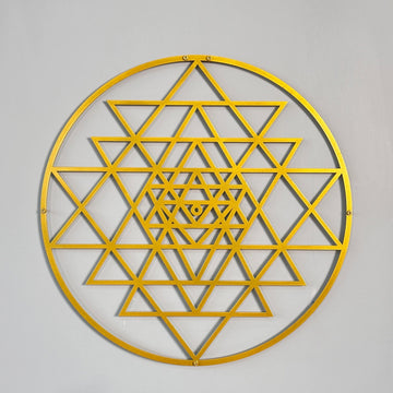 Altın renkli daire Sri Yantra metal duvar tablosu, gri duvarda önden tam görünüm