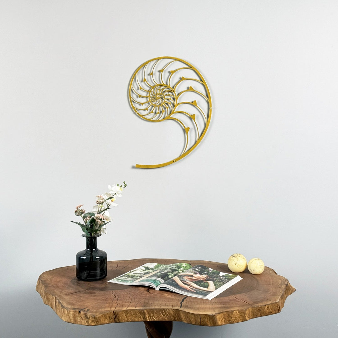 Altın renkli Nautilus Altın Oran spiral metal duvar tablosu, kütük masa ve çiçekli vazonun üstünde