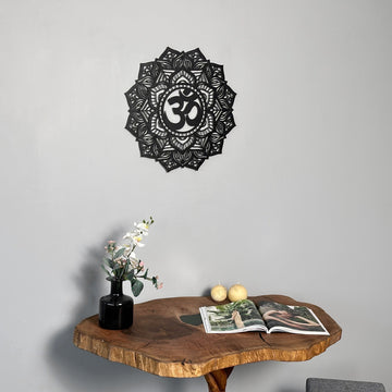 Siyah OM mandala metal tablo, 47x47 cm, masanın üzerindeki duvarda, orkideli vazo yanında