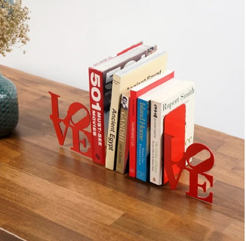 Kırmızı LOVE yazılı metal kitap tutucu, ahşap masa üzerinde yan açıdan görünüm