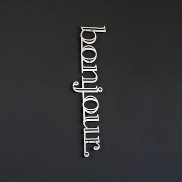 Bonjour yazılı metal duvar dekoru, Gümüş renk, koyu duvarda küçük kadraj