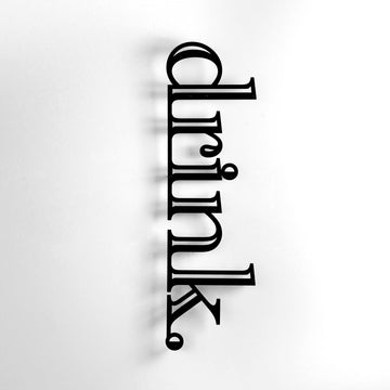 Siyah renk Drink yazılı metal duvar dekoru, aydınlık duvarda yakın kadraj
