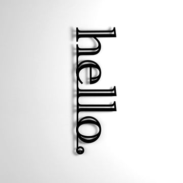 Siyah hello yazılı metal duvar dekoru, beyaz duvarda hafif gölgeli karşıdan çekim
