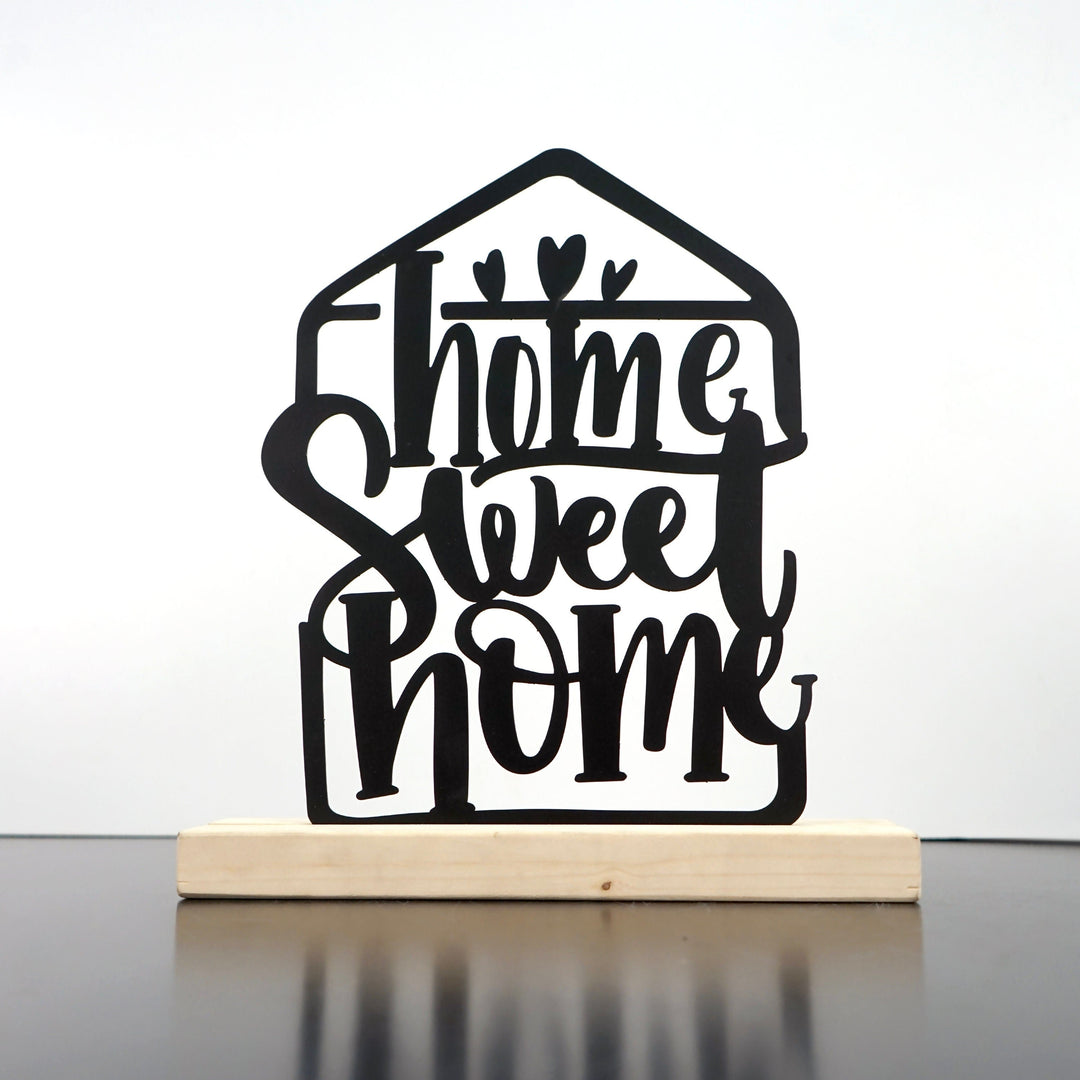 Siyah Home Sweet Home metal masa dekoru, açık renkli masif ahşap altlıkta önden görünüm