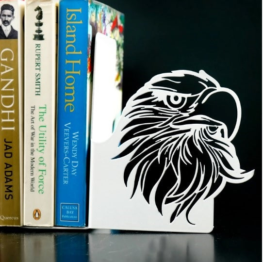 Beyaz metal kitap tutucudaki kartal başı oyma deseninin siyah fonda yakın çekimi